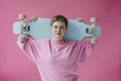 Portrait of teenage girl standing against pink background