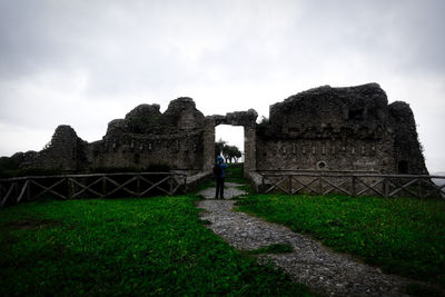 Man walking in front of historical building against sky