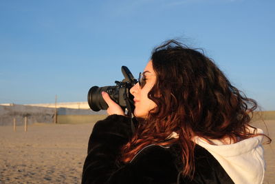 Portrait of woman standing on beach against clear sky