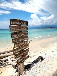 Information sign on beach against sky