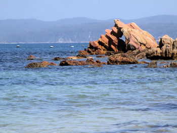 Rocks by sea against clear sky