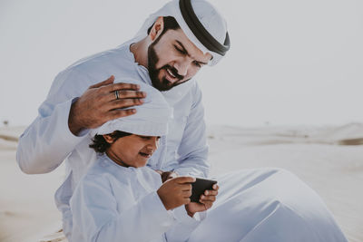 Rear view of man holding smart phone while standing outdoors