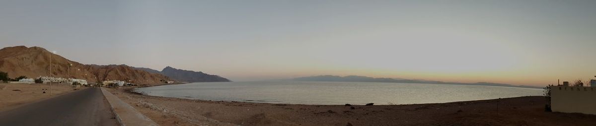 Panoramic view of road by sea against sky during sunset