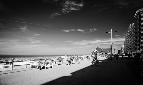 People on beach against sky in city