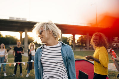 Smiling young man enjoying with friends in music event on sunny day