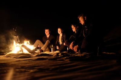 Friends sitting by bonfire at night