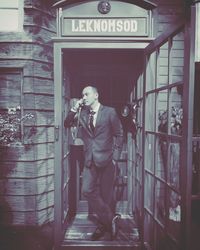 Full length of man using telephone booth