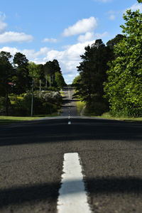 Surface level of road by trees in city against sky