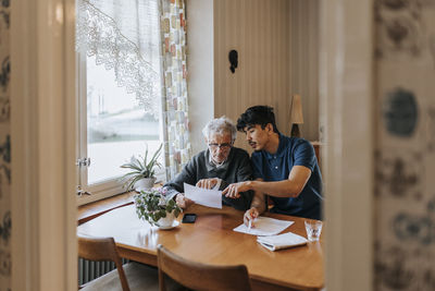 Male caregiver explaining medical reports to senior man at home