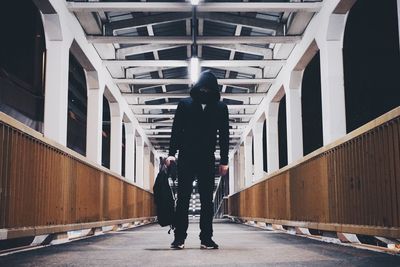 Man standing on illuminated footbridge at night