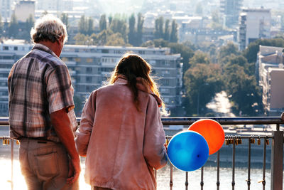 Rear view of man and woman standing against cityscape