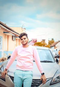 Portrait of young man standing against car