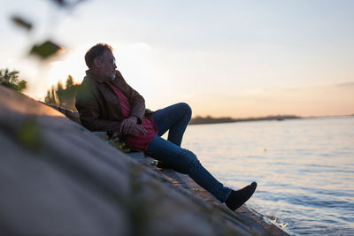 Lonely man sitting on stairs next to the river bank