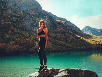 Portrait of young woman standing on rock against mountain