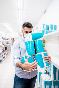 Mountain of toilet paper packages held by a man before purchase in a supermarket.t. stock piling 