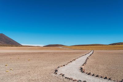 Scenic view of desert against clear blue sky