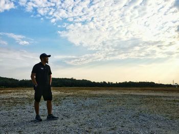 Full length of man with hands in pockets standing against sky