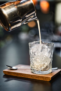 Close-up of ice pouring in glass on table