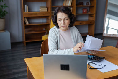 Young woman using laptop while sitting on table