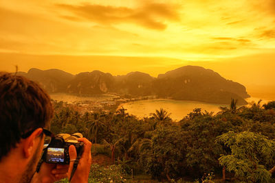 Woman photographing through smart phone at sunset