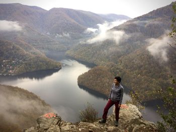 Woman hiking over mountain lake in foggie autumn morning