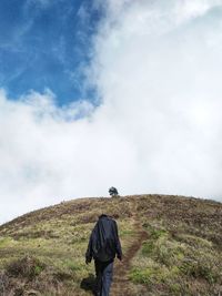 Rear view of man on field against sky