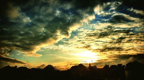 Silhouette houses against sky during sunset
