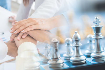 Double exposure of business people stacking hands and chess pieces