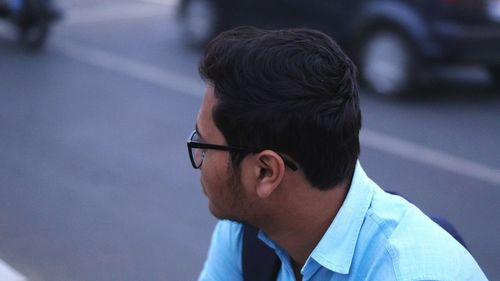 Close-up of man wearing eyeglasses looking away in city