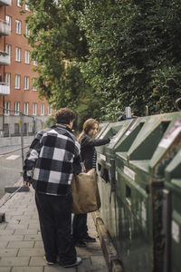 Girl trashing garbage with teenage male friend on footpath