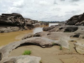 Rock formation on beach against sky