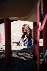 Girl at playground seen through play equipment