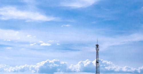 Mobile telecommunication tower with communication antennas in the background of dense clouds