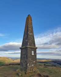 Low angle view of obelisk against cloudy sky