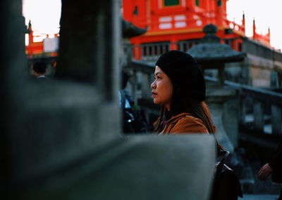 Side view of woman looking away in city against buildings