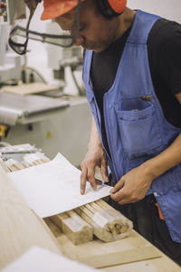 Carpenter worker reading blueprint while working in warehouse