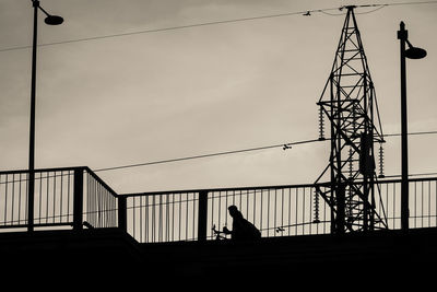 Low angle view of silhouette people on railing against sky