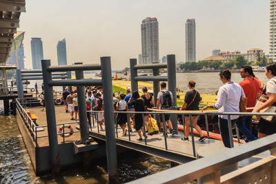 People standing by railing against buildings in city