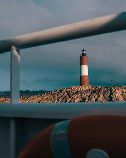 Lighthouse by sea against sky