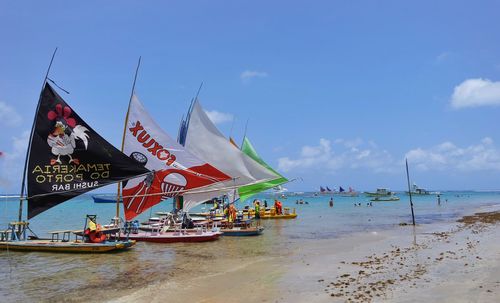 People on boat at beach against sky