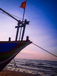 Silhouette sailboat on beach against sky during sunset