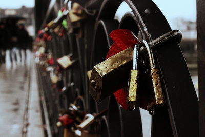 Close-up of wet love locks hanging on bridge railing