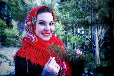 Portrait of beautiful young woman standing against red trees