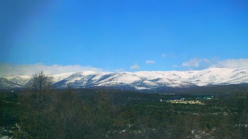 Scenic view of snowcapped mountains against blue sky