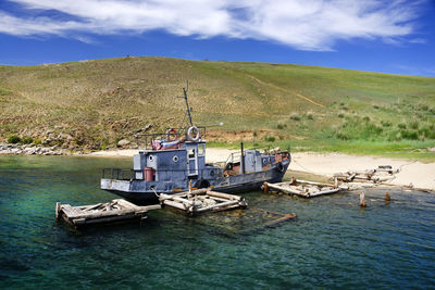 Boat moored at lakeshore by mountain against sky