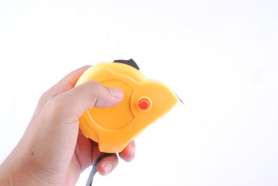 Close-up of person holding yellow toy against white background