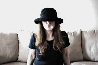 Young woman wearing hat sitting on sofa