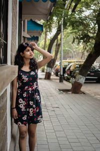 Young woman looking away while standing on sidewalk