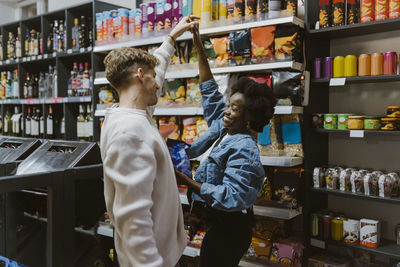 Romantic multiracial couple dancing while doing shopping at supermarket