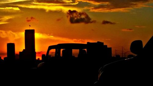 Silhouette factory against sky during sunset